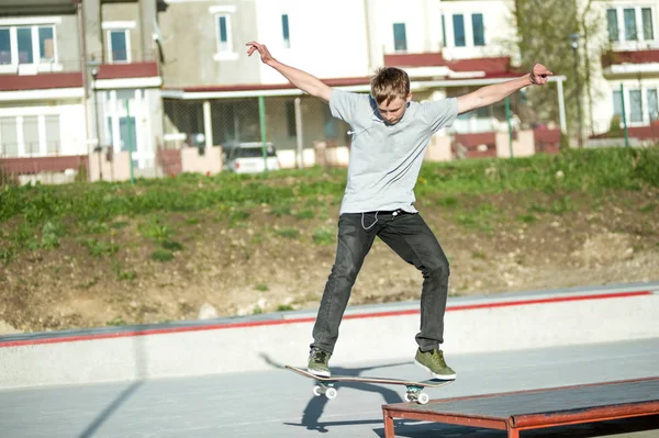 Genç bir adam bir kılavuzda bir kaykay üzerinde bir skatepark evin arka plan üzerinde slaytlar — Stok fotoğraf