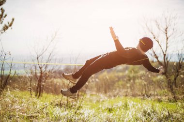 Sakallı ve güneş gözlüklü bir adam germe bir ip ya da açık havada bahar slaskening doğada açık hava bir gölgelik Dengeleme yalan