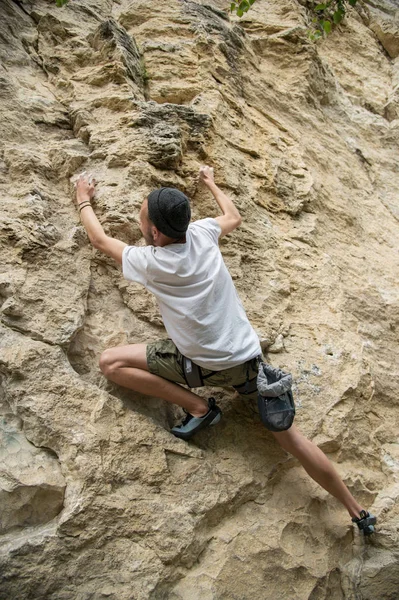 A young man is engaged in rock climbing on a steep rock without insurance — Stock Photo, Image