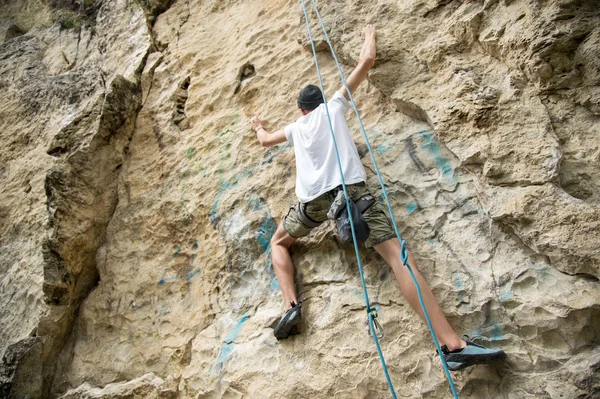 Un giovane uomo è impegnato nell'arrampicata su una roccia ripida senza assicurazione — Foto Stock