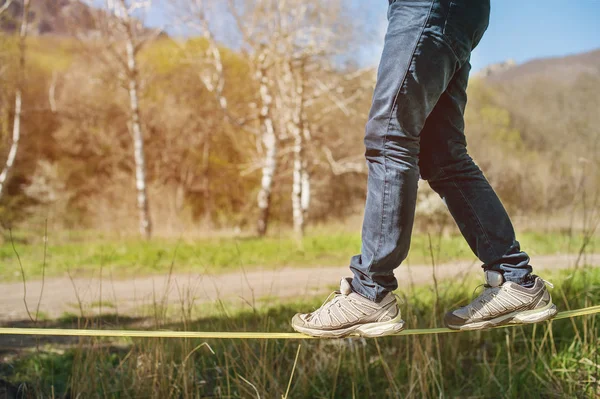 Slacklining es una práctica de equilibrio, en la que se utiliza comúnmente tela de nylon o poliéster estirada entre dos puntos de anclaje. La gente camina y hace trucos. — Foto de Stock