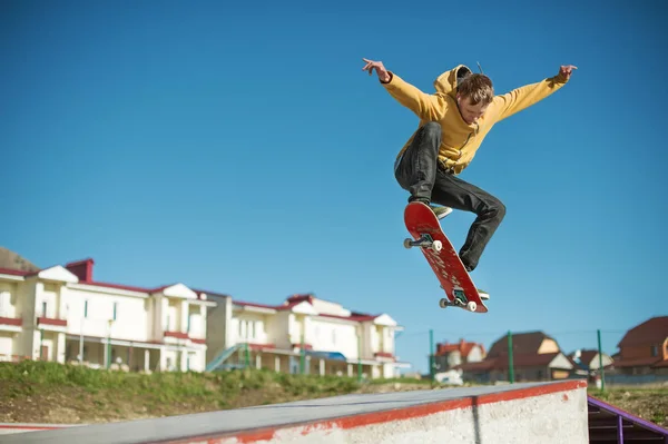 Egy tinédzser gördeszkás csinál egy ollie trükk egy skatepark, a város szélén — Stock Fotó