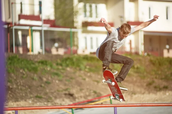 Egy tinédzser gördeszkás csinál egy ollie trükk egy skatepark, a város szélén — Stock Fotó