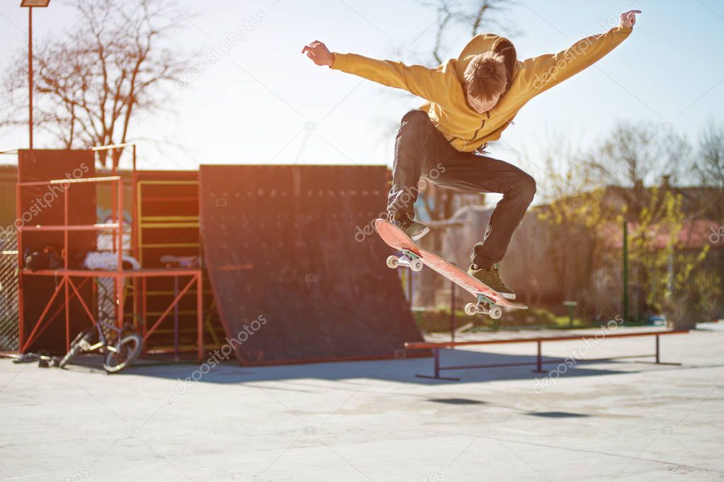 A teenager skateboarder does an ollie trick in a skatepark on the outskirts of the city