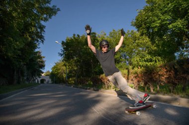 Bir genç adam eylem bir longboard stand-up slaytta şehir tesisi alanı yapar.