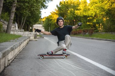 Bir genç adam eylem bir slayt bir longboard üzerinde şehrin tesisi alanı yapar.