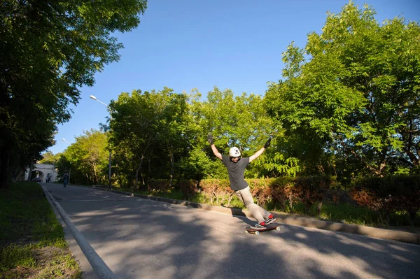 A young guy action makes a stand-up slide on a longboard in the resort area of the city — Stock Photo, Image