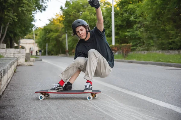 Akcji młody facet sprawia, że slajd na longboard w dzielnicy uzdrowiskowej miasta — Zdjęcie stockowe