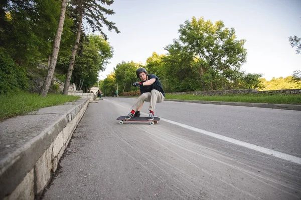 Un chico joven de acción hace una diapositiva en un longboard en la zona turística de la ciudad — Foto de Stock