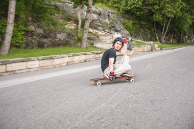 Bir genç adam eylem bir slayt bir longboard üzerinde şehrin tesisi alanı yapar.