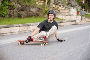 Bir genç adam eylem bir slayt bir longboard üzerinde şehrin tesisi alanı yapar.