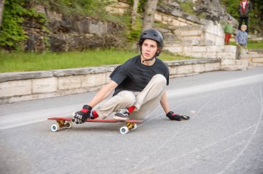 A young guy action makes a slide on a longboard in the resort area of the city clipart