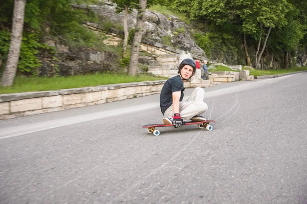 Bir genç adam eylem bir slayt bir longboard üzerinde şehrin tesisi alanı yapar. — Stok fotoğraf