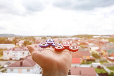 Bir iki spinners makine el oyuncak Kıpırdanmayı cityscape arka plan üzerinde tutan bir adamın elini Close-Up