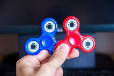 Elini tutan iki çok renkli spinners kişisel bilgisayar yakın çekim arka plan üzerinde mans