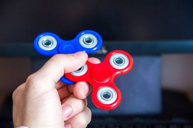 Elini tutan iki çok renkli spinners kişisel bilgisayar yakın çekim arka plan üzerinde mans