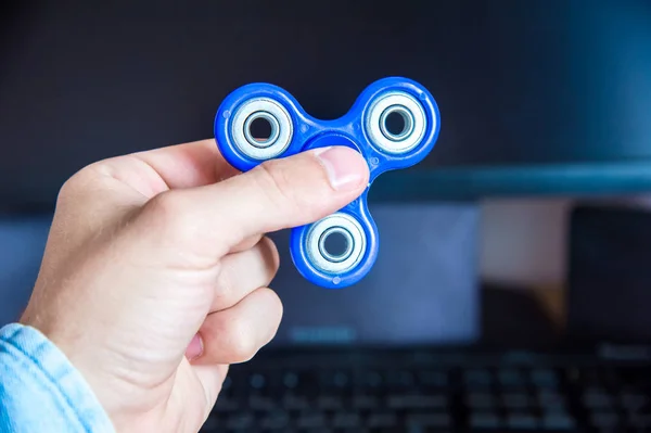 Mans hand holds a spinner on the background of a personal computer close-up — Stock Photo, Image