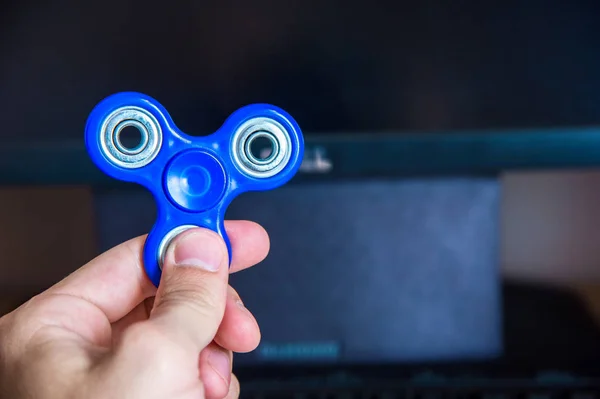Mans hand holds a spinner on the background of a personal computer close-up — Stock Photo, Image
