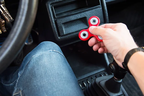 Close-up of a mans hand playing with a spinner while in a traffic jam on the background of the cars interior — Stock Photo, Image