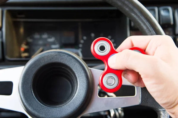 Gros plan d'un homme main jouant avec une spinner tandis que dans un embouteillage sur le fond de l'intérieur des voitures — Photo