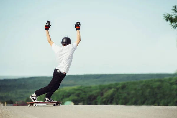 Ein junger Kerl vollführt einen komplexen Trick auf dem Longboard — Stockfoto