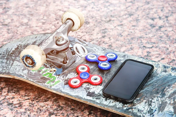 Close-up Spinners next to the phone on the skateboard — Stock Photo, Image