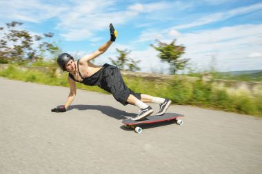 Kask içinde genç adam slayt, sparks ile bir longboard asfalt üzerinde slayt gidiyor