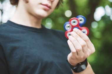 Bir kap içinde uzun saçlı bir hippi bir bankta oturur ve topluca spinner döner