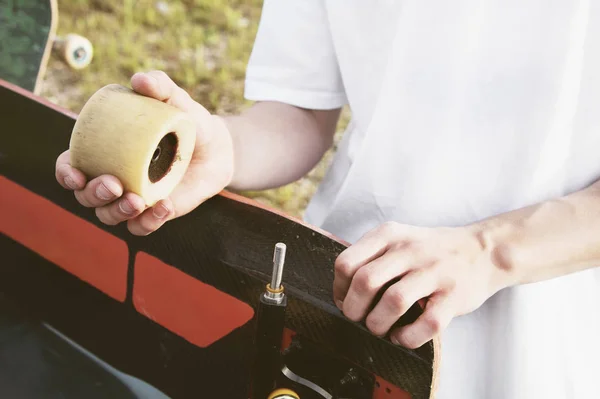 Un primer plano de un joven cambia sus ruedas en su longboard y ajusta la suspensión . — Foto de Stock