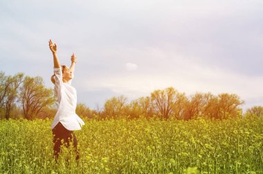 Doğa ve özgürlük zevk ve hayatın tadını çıkarırken bir kız açık havada, güzellik. Güzel kız Beyaz gömlekli, elini kolunu sallaya dönüyor bir bahar sahada güneş ılık ışık.