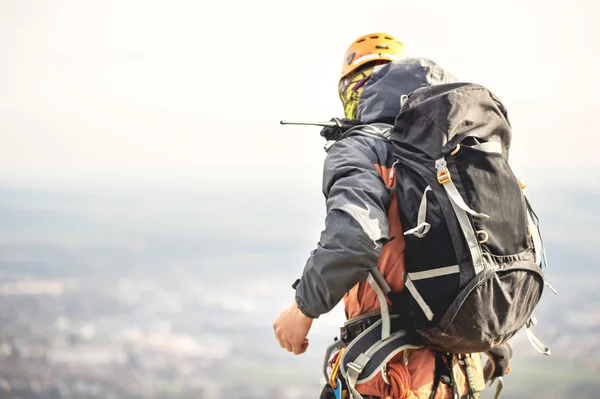 Primer plano de un escalador desde atrás en marcha y con una mochila con equipo en el cinturón, se encuentra en una roca, a gran altitud — Foto de Stock