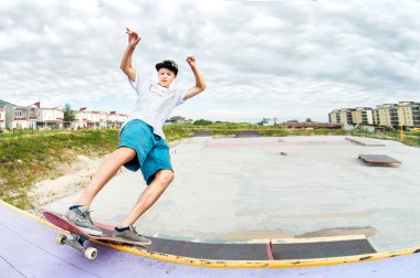 Bir kap ve şort bir skate Park bir kaykay üzerinde raylar üzerinde genç patenci
