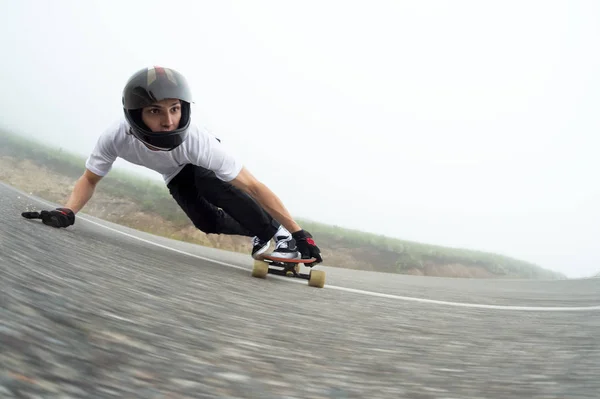 Um jovem em um capacete de rosto cheio em um slide passa por uma curva — Fotografia de Stock