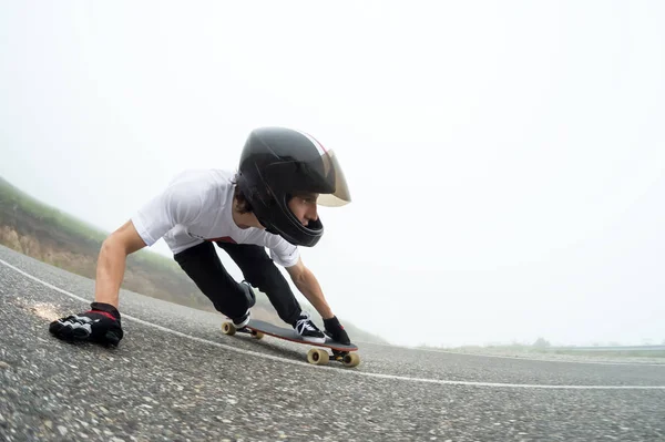 Um jovem em um capacete de rosto cheio em um slide passa por uma curva — Fotografia de Stock
