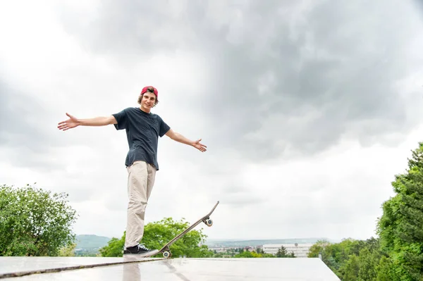 Ein junger Skater steht mit einem Skateboard vor dem Hintergrund der Landschaft der Stadt — Stockfoto