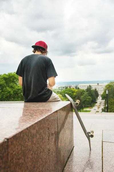 Skater sits with his back and thinks next to the skateboard — Stock Photo, Image