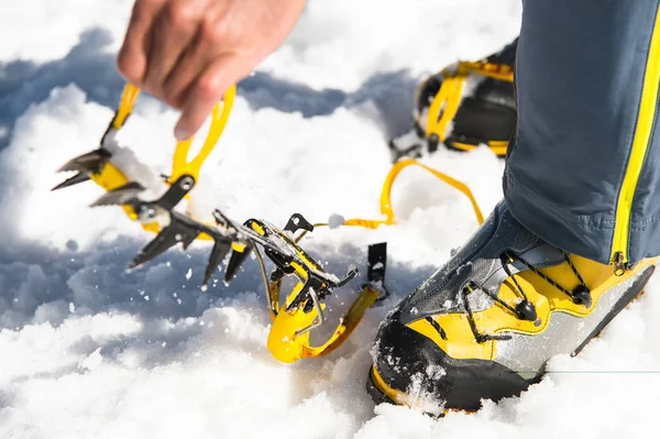 A young guy hiker dresses climbing Crampons over mountaineering shoes For walking through Glacier — Stock Photo, Image