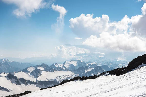 Donker blauwe hemel met wolken op de rotsige toppen van de bergen bedekt met gletsjers en sneeuw — Stockfoto