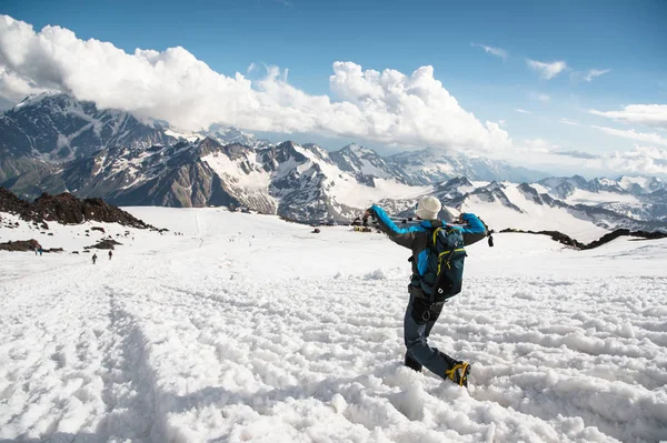 De vermoeide reiziger afstamt van de besneeuwde top tegen de achtergrond van met sneeuw bedekte bergen — Stockfoto