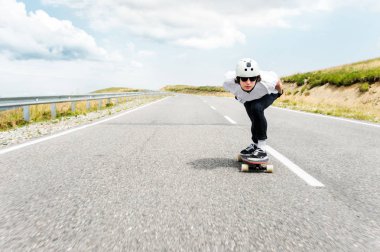 Kask ve güneş gözlüğü takan bir adam onun longboard bir ülke yolda biniyor