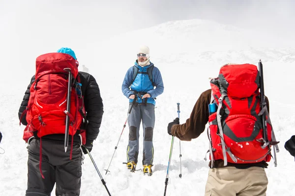 Een team van klimmers onder leiding van een gids bespreekt de aankomende beklimming — Stockfoto