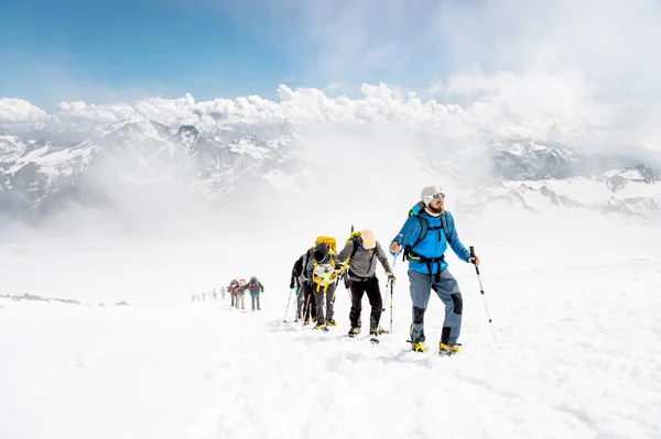 Grupa alpinistów wspina się na szczyt, ośnieżone góry — Zdjęcie stockowe