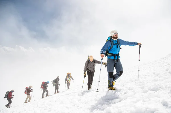 Un groupe d'alpinistes monte au sommet d'une montagne enneigée — Photo