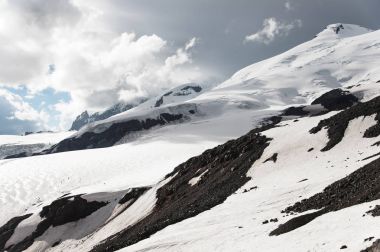 Fırtınalı bulutlar çıkıntı karla kaplı dağ Elbrus üzerinde