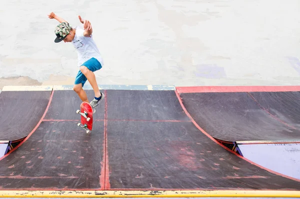 Patinador adolescente cuelga sobre una rampa en un monopatín en un parque de skate — Foto de Stock