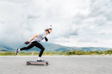 Genç Longboarder ayağını onun longboard üzerinde ülke yolu üzerinden iter