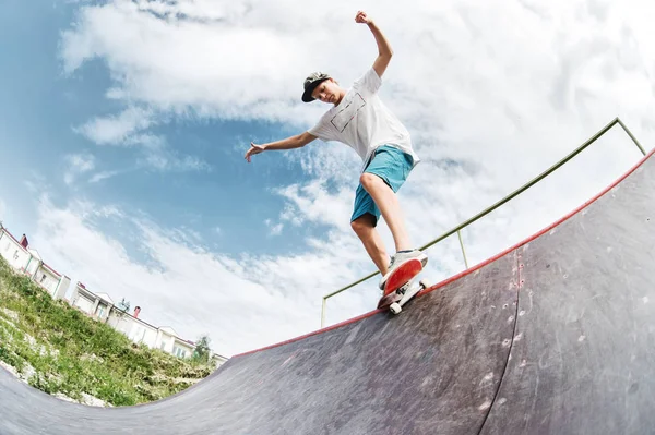 Adolescente skatista pendurar sobre uma rampa em um skate em um parque de skate — Fotografia de Stock