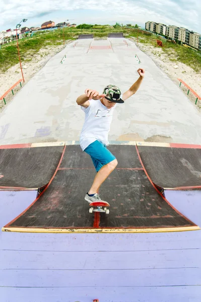 Teen skater rides over a ramp on a skateboard in a skate park — Stock Photo, Image