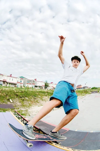 Teen bruslař zavěsit nad rampou na skateboardu v skate parku — Stock fotografie