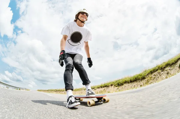 De jonge Longboarder duwt zijn voet uit op zijn longboard over de landweg — Stockfoto